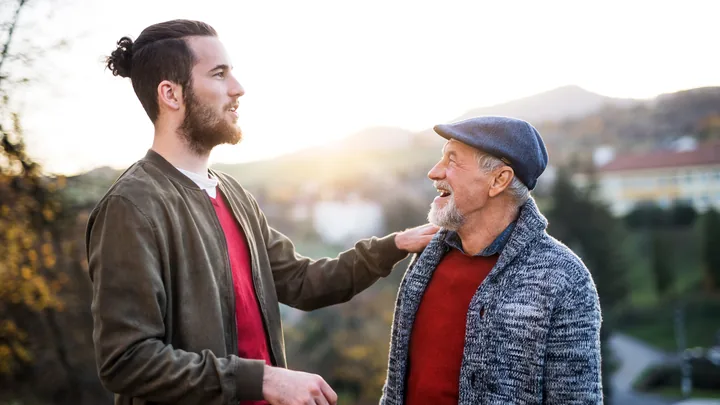 A father and his grown son walking and talking on a country path in evening light.